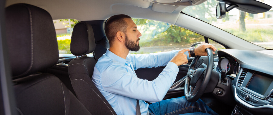 A man in a car looking at his watch