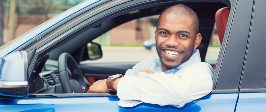 African american smiling looking at the camera while sitting in the drivers seat of a car