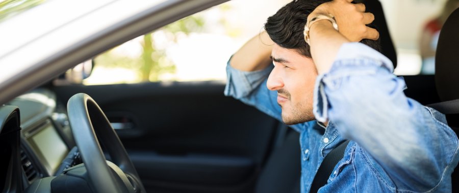 Stressed out man in car with hands on his head