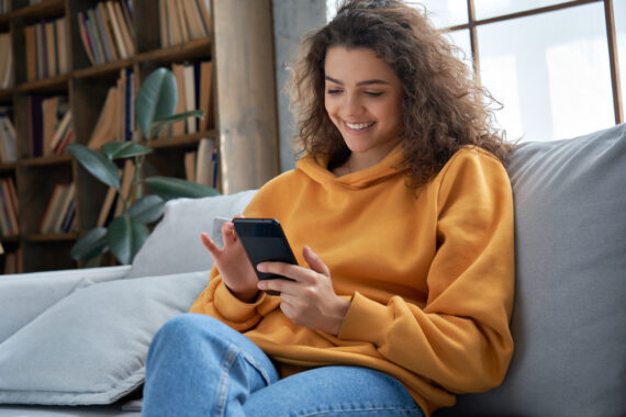 young hispanic woman sitting on couch on cell phone