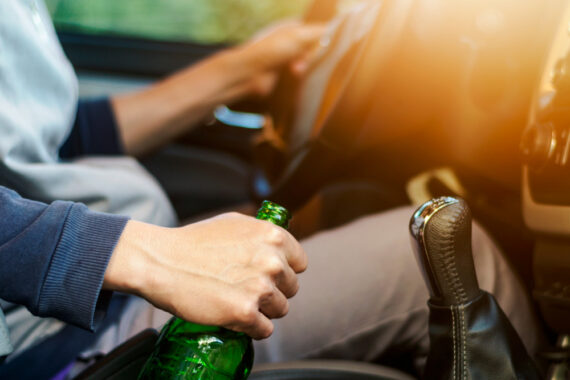 person driving with beer bottle in hand