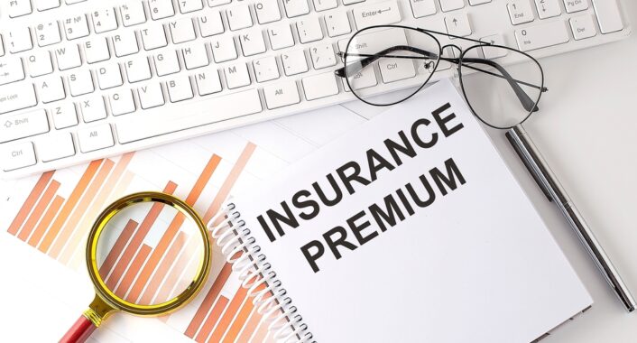 document that says insurance premium next to keyboard and pair of glasses