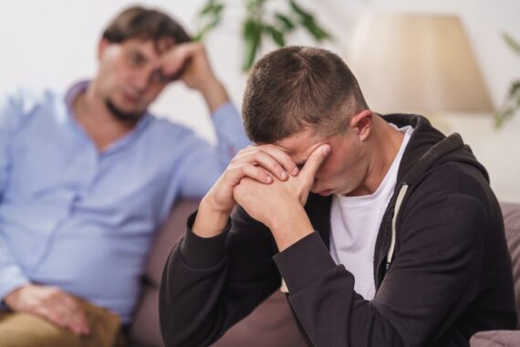 man sitting on couch with head in hands