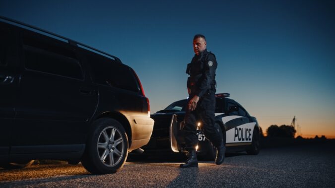 A police officer walks up to a car driven by someone with no car insurance