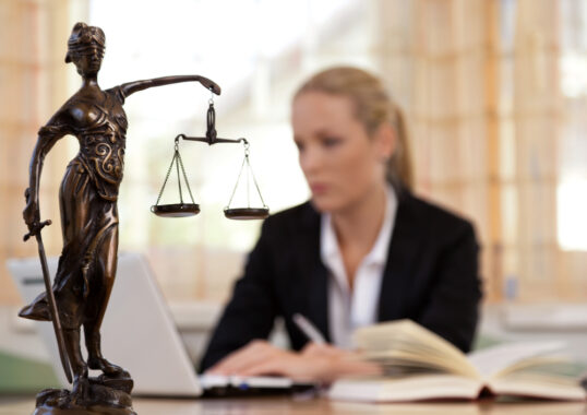 Woman attorney sits behind scales of justice