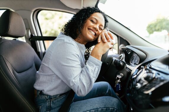 Happy young woman higs her steering wheel in relief - cheap SR22 insurance