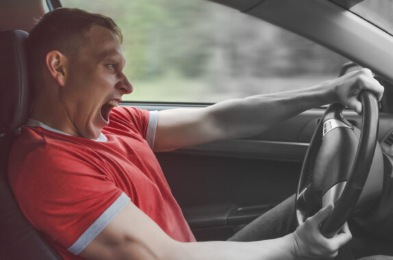 Man driving crazy behind the wheel of a car - cheap SR22 insurance