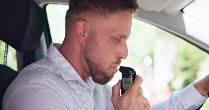 Man breathing into a car breathalyzer