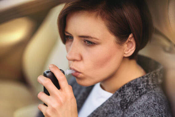 Millennial woman breathing into a breathalyzer.