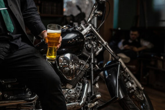 Man sitting on his motorcycle with a beer in hand.